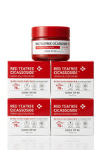 A stack of red and white boxes of Red Teatree Cicassoside Derma Solution Cream, with one open jar with a red lid placed on top, set against a plain white background. in Dubai 